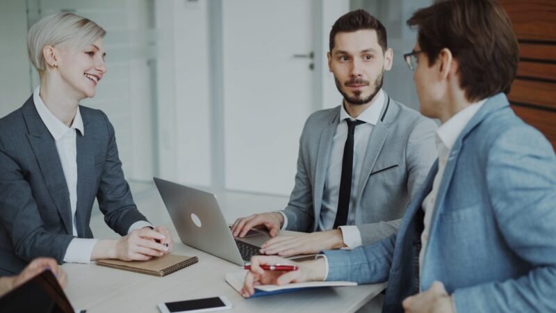 Inicio 1: Papeles iniciales para la Venta Business professionals in a meeting around a table.